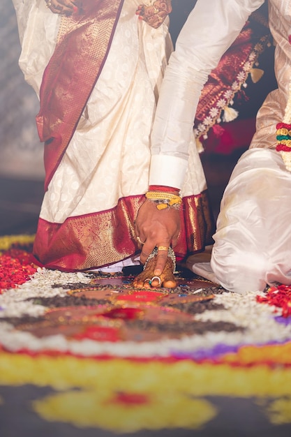 Foto sezione bassa della sposa e dello sposo in abiti tradizionali durante la cerimonia nuziale