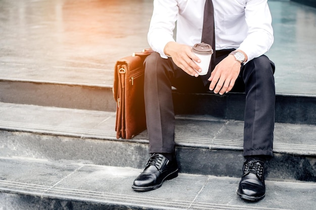 Photo low section of businessman having coffee while sitting on steps