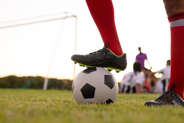 Low section of caucasian male athlete wearing red socks and black shoes putting leg on soccer ball