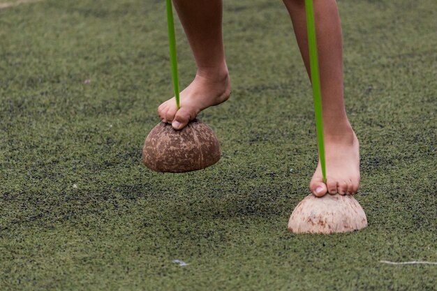 Low section of child walking on coconut shells at field