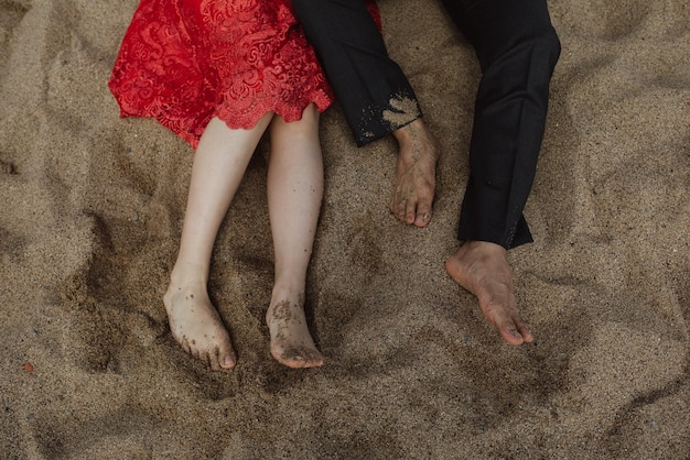 Photo low section of couple lying on sand at beach