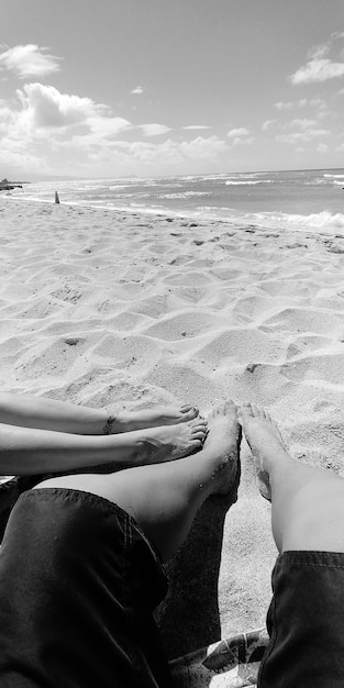 Low section of couple relaxing at beach