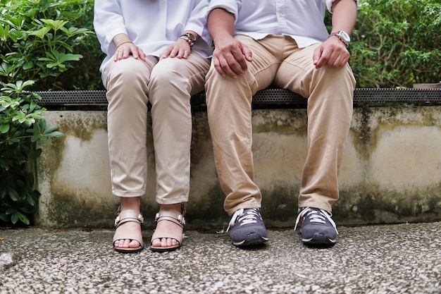 Photo low section of couple sitting on bench
