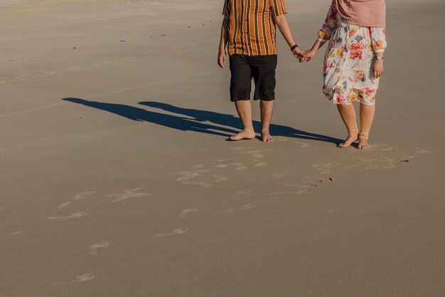 Photo low section of couple walking on sand at beach