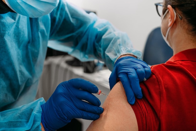 Low section of doctor giving vaccine injection to patient
