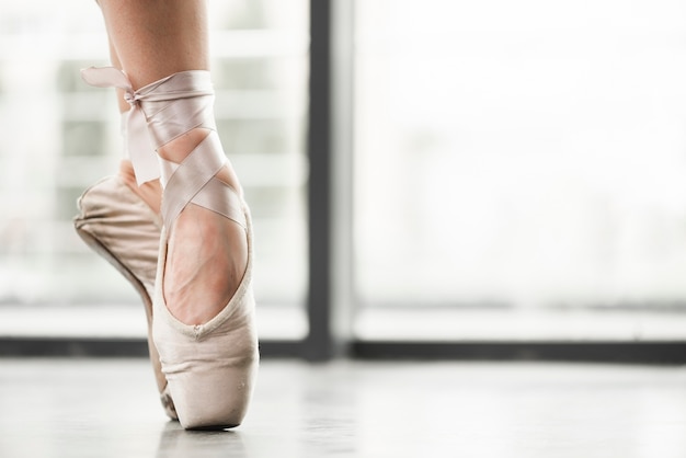 Low section of female dancer wearing ballet shoes standing on tiptoes