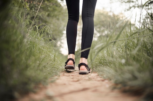 Sezione bassa dei piedi della viandante femminile che cammina sulla pista