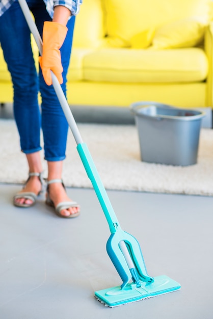 Low section of female janitor cleaning the floor with mop