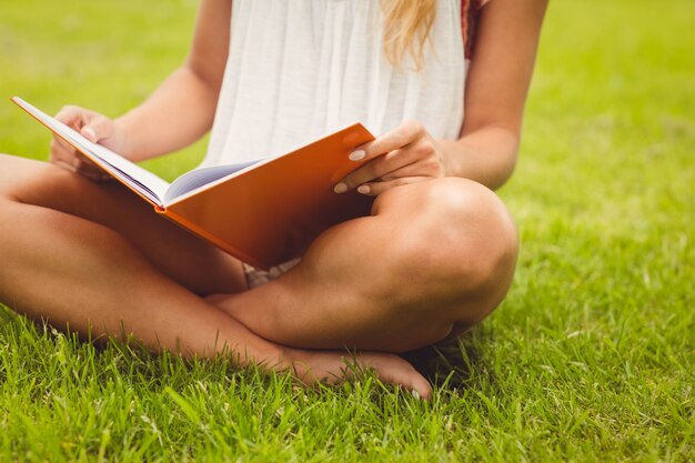 Low section of female student reading book 
