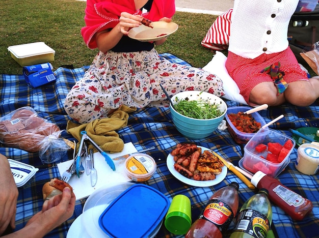 Low section of friends having meal at picnic