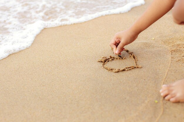 Foto sezione bassa di una ragazza che gioca sulla sabbia sulla spiaggia