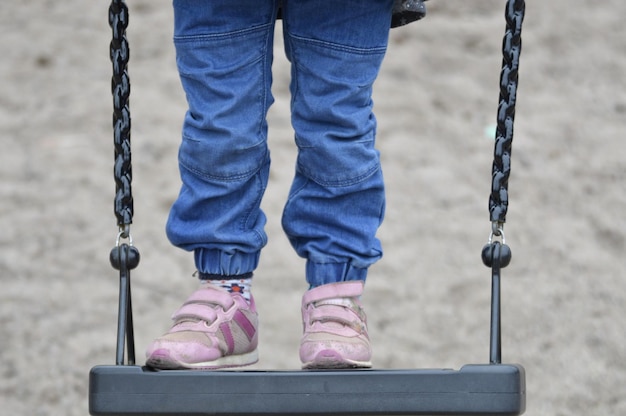 Foto sezione bassa della ragazza in piedi sull'altalena