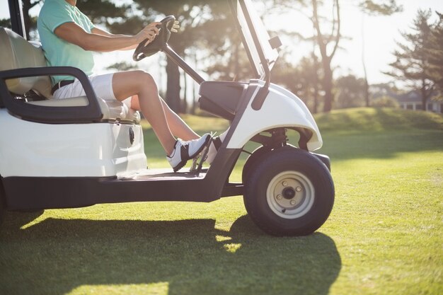 Low section of golfer man driving golf buggy