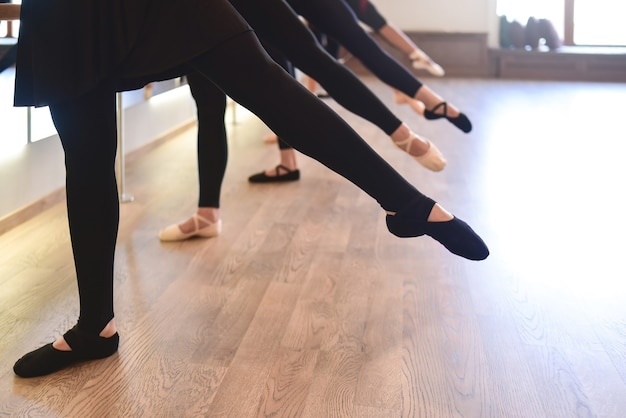 Foto sezione bassa delle gambe aggraziate dei ballerini in fila eseguono esercizi di stretching