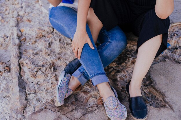 Photo low section of lesbian couple sitting at beach