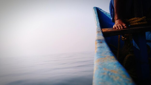 Photo low section of man on boat in sea against sky