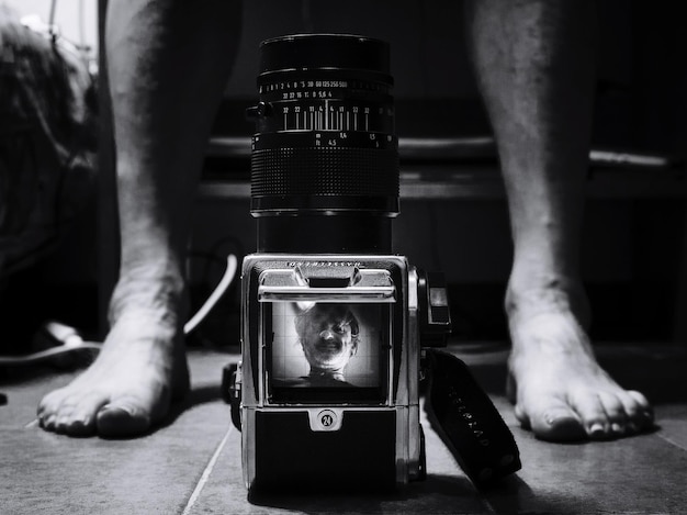 Photo low section of man by digital camera on floor at home