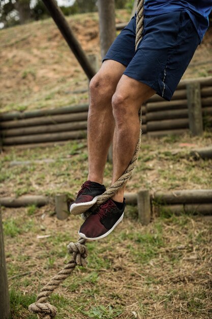 Low section of man climbing a rope during obstacle course