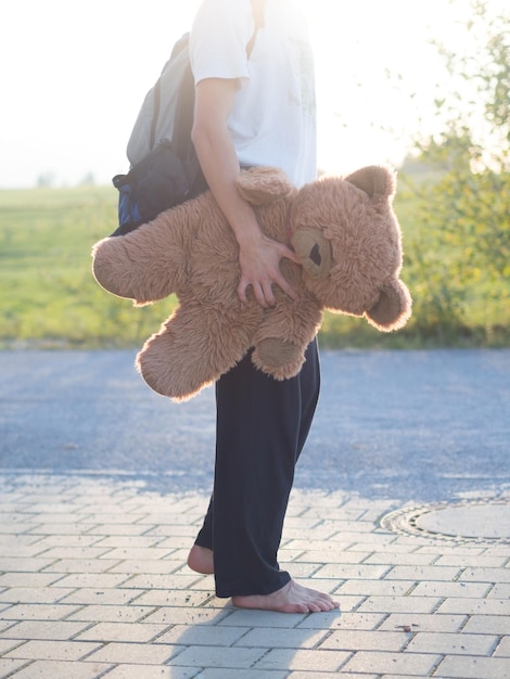 Photo low section of man holding teddy bear on footpath