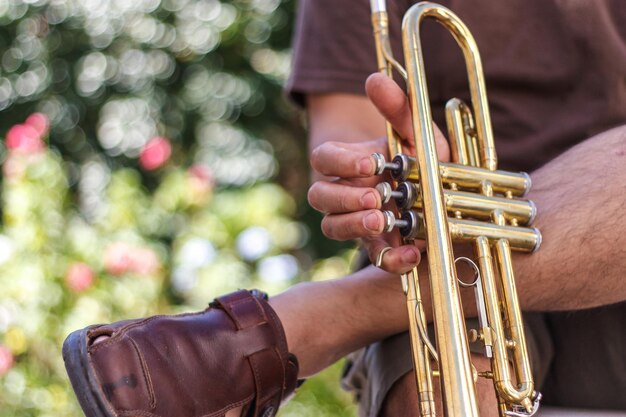 Photo low section of man holding trumpet sitting outdoors