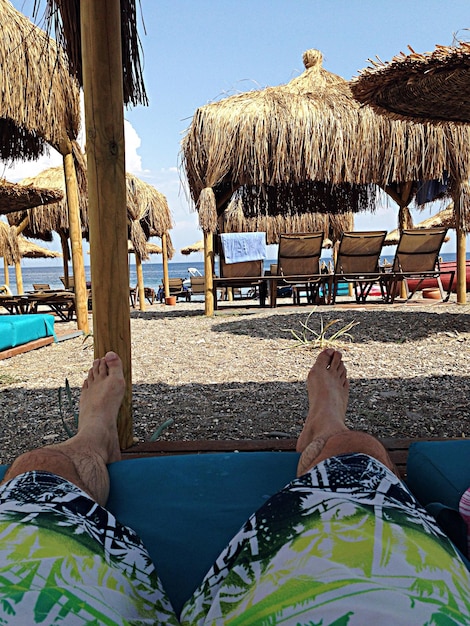 Photo low section of man lying under shade at beach