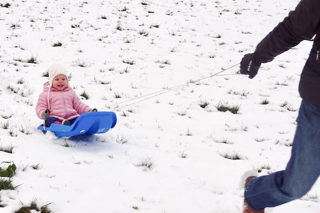 Photo low section of man pulling sled with child on snow covered field