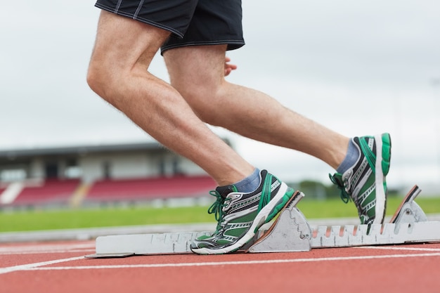 Low section of a man ready to race on running track