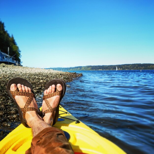 Low section of man relaxing against blue sky