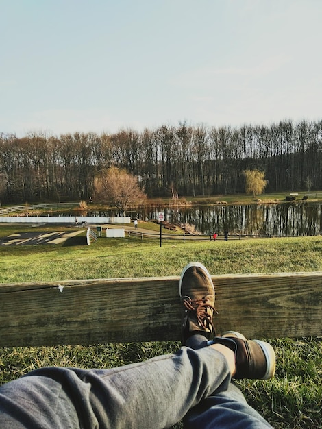 Photo low section of man relaxing against lake on field