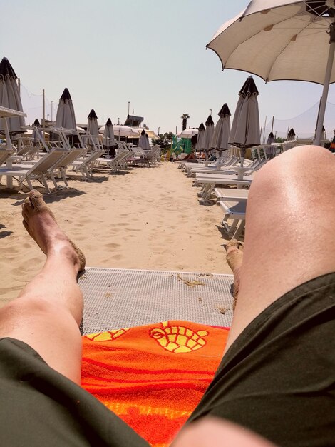 Low section of man relaxing at beach