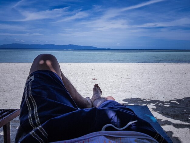 Photo low section of man relaxing at beach