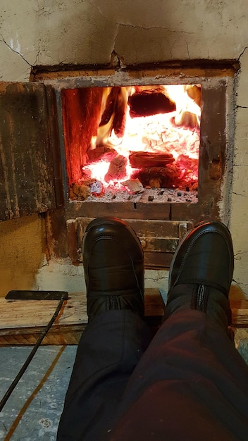 Photo low section of man relaxing by fireplace