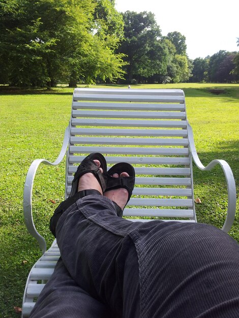 Foto sezione bassa di un uomo che si rilassa su una poltrona al parco