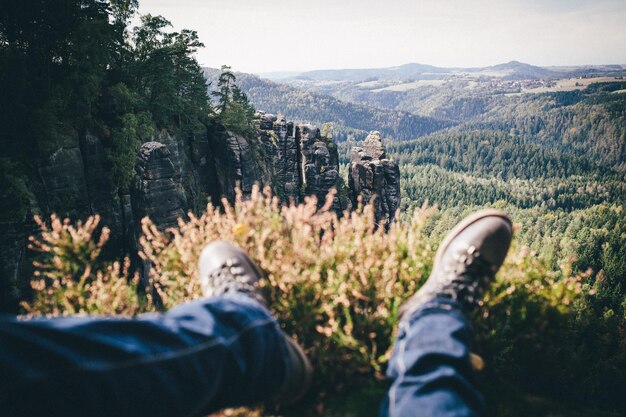 Foto sezione bassa dell'uomo che si rilassa sulla montagna nella foresta