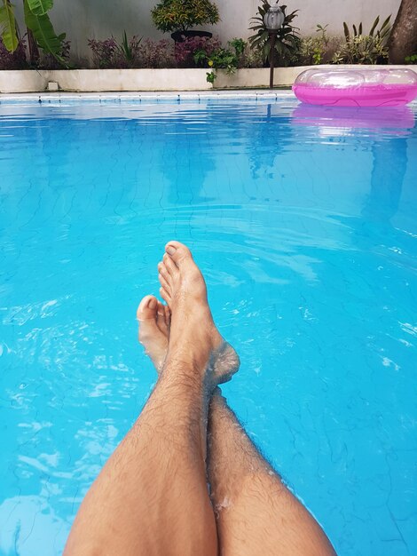 Low section of man relaxing in swimming pool