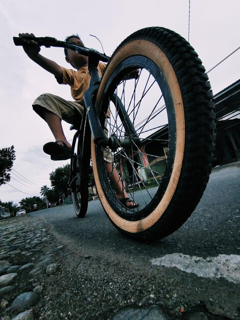 Low section of man riding bicycle against sky