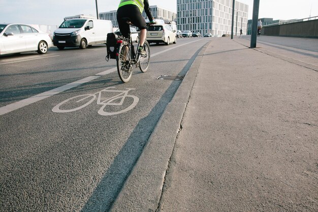 Photo low section of man riding bicycle on road in city