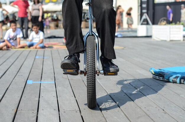 Photo low section of man riding unicycle on hardwood floor