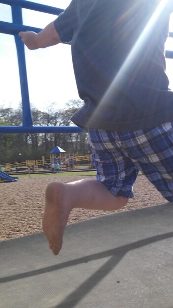 Photo low section of man running on footbridge at playground during sunny day