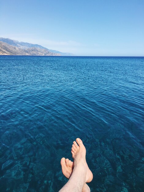 Low section of man in sea against sky