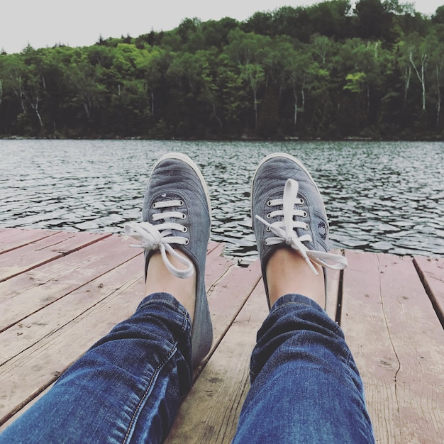 Foto sezione bassa di un uomo seduto sul molo sopra il lago