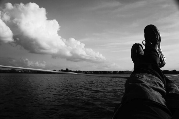 Low section of man sitting at beach against sky