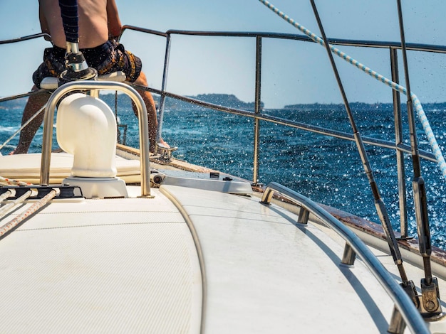 low section of man sitting on boat in sea during sunny day