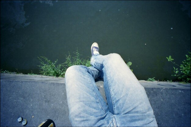 Low section of man sitting over calm water