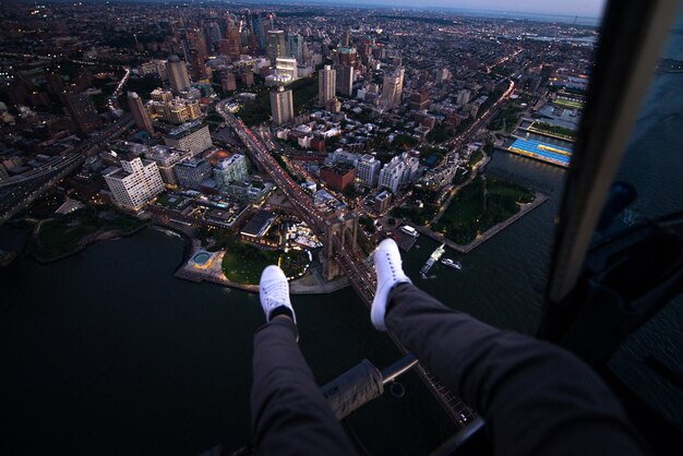 Foto sezione bassa di un uomo seduto in elicottero sopra gli edifici della città