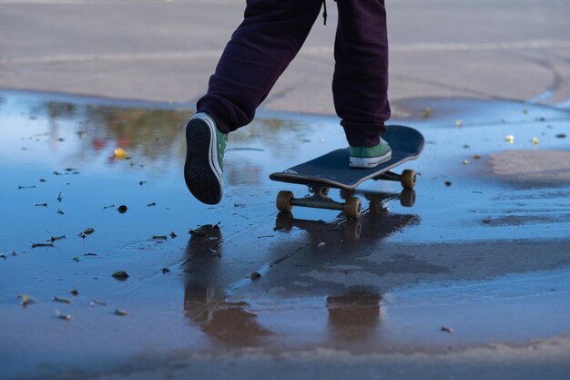 low section of man skateboarding on puddle