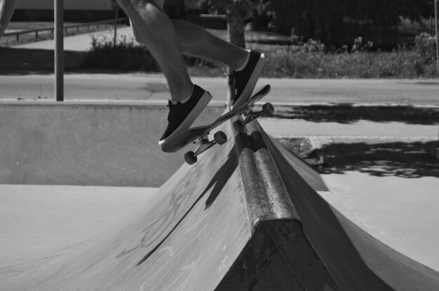 Foto sezione bassa di un uomo che fa skateboard allo skate park