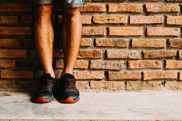 Photo low section of man standing against brick wall