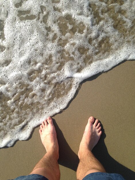 Foto sezione bassa di un uomo in piedi sulla spiaggia