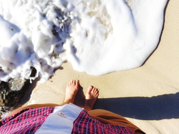 Low section of man standing on beach